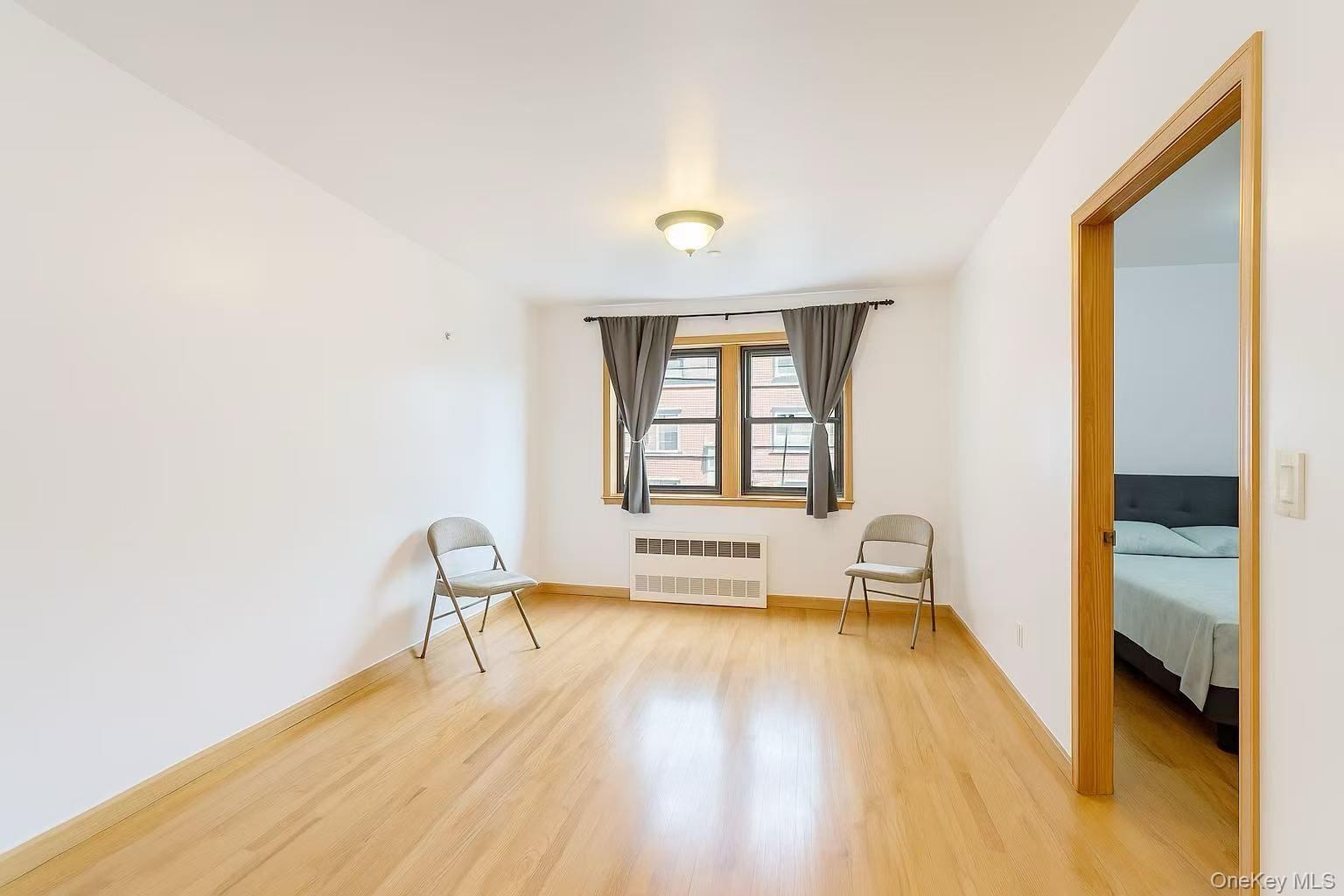 46-06 88th Street, Unit 5B Queens, NY 11373 - Photo 6 of 11 Spare room with light wood finished floors and radiator