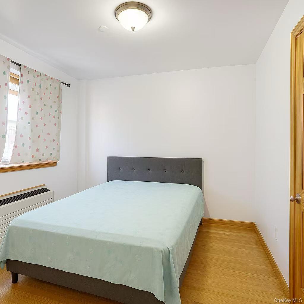 46-06 88th Street, Unit 5B Queens, NY 11373 - Photo 7 of 11 Bedroom featuring light wood-style floors and radiator heating unit