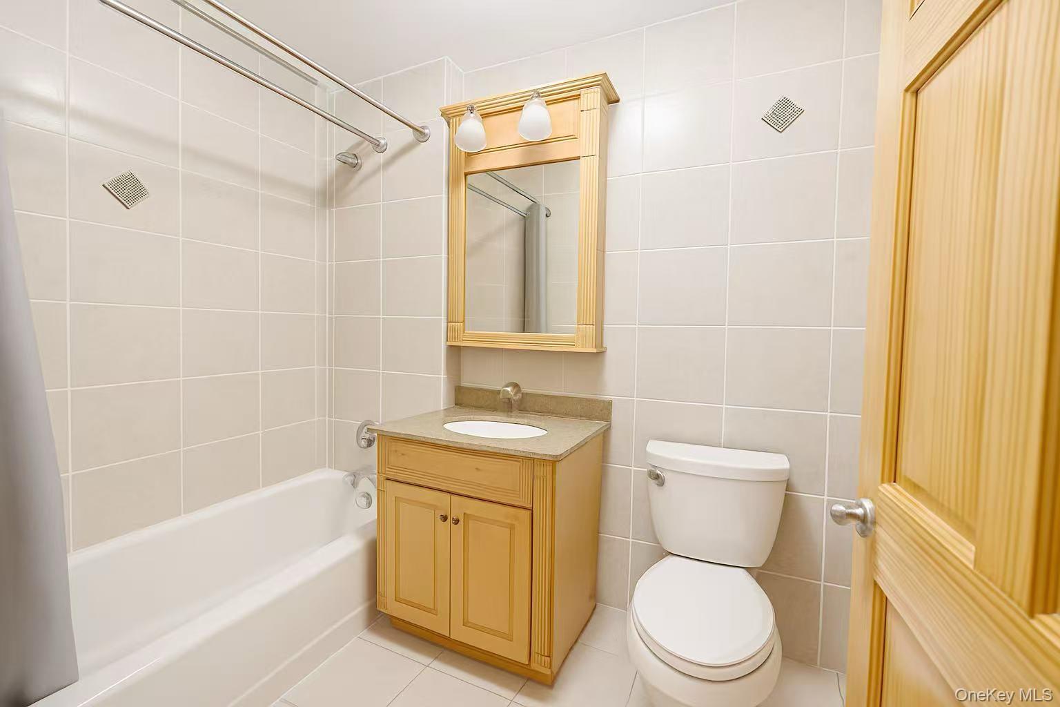 46-06 88th Street, Unit 5B Queens, NY 11373 - Photo 9 of 11 Bathroom with tile walls, vanity, shower combination, and tile patterned flooring
