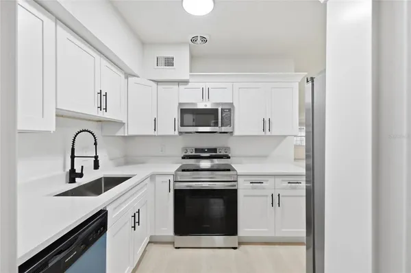 a kitchen with white cabinets and stainless steel appliances