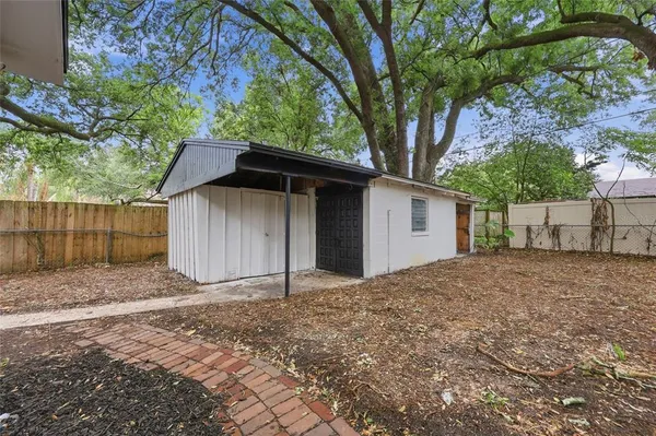 a backyard of a house with large trees and wooden fence