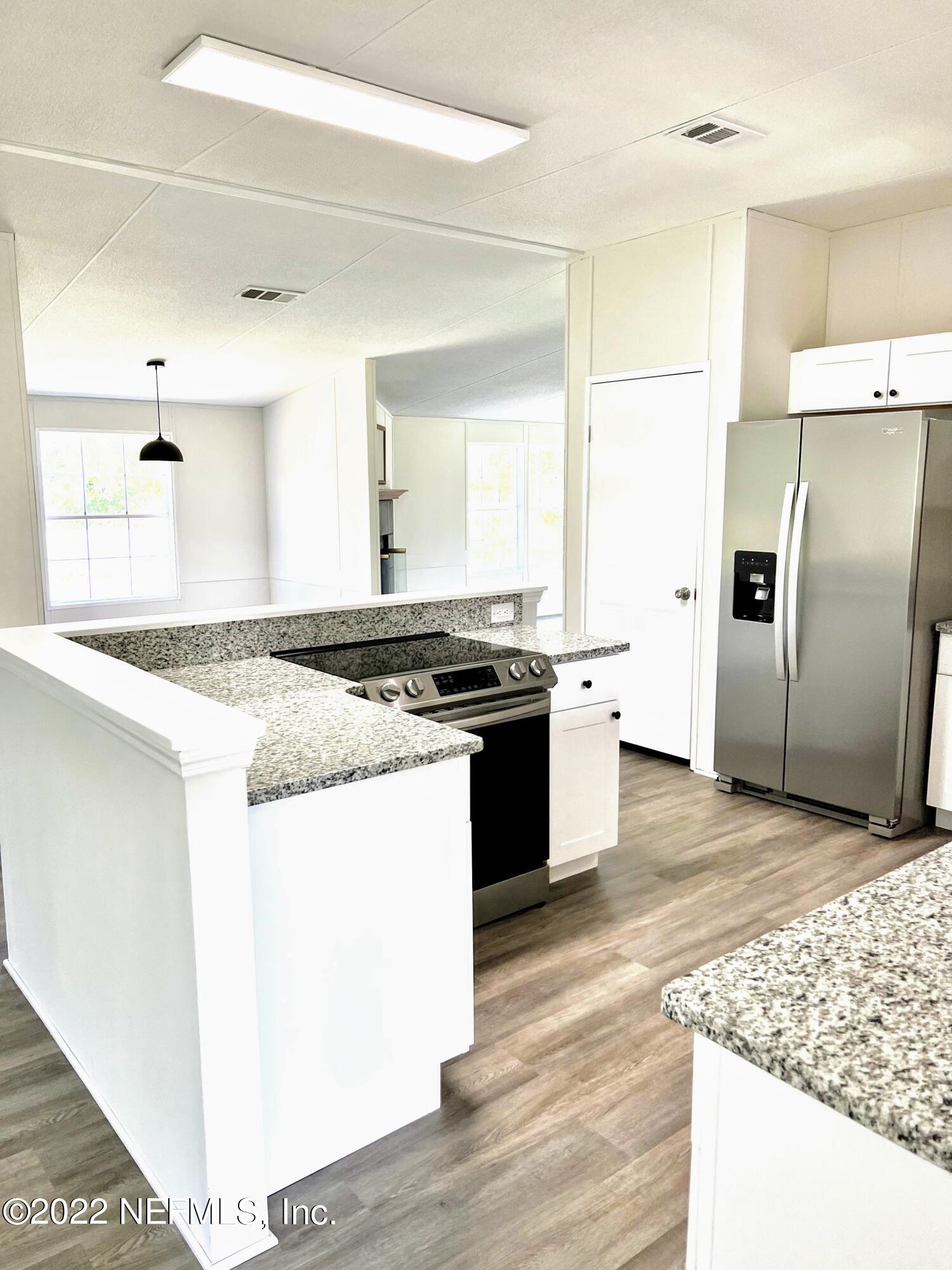 54176 Armstrong Road Callahan, FL 32011 - Photo 11 of 30 a kitchen with granite countertop a stove and a refrigerator