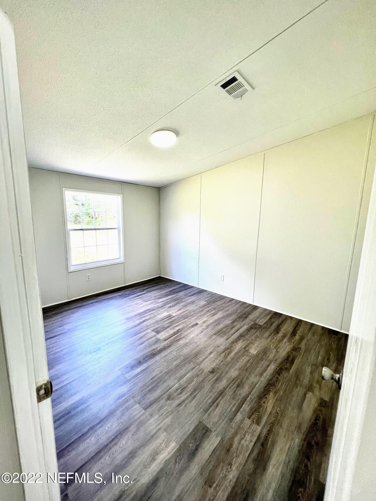 54176 Armstrong Road Callahan, FL 32011 - Photo 23 of 30 an empty room with wooden floor and windows