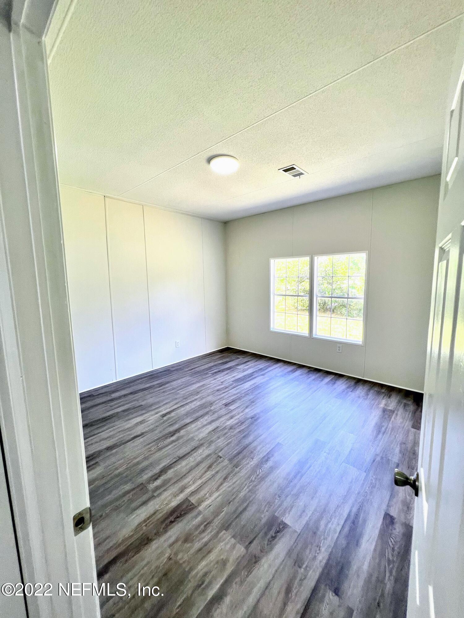 54176 Armstrong Road Callahan, FL 32011 - Photo 26 of 30 an empty room with wooden floor and windows