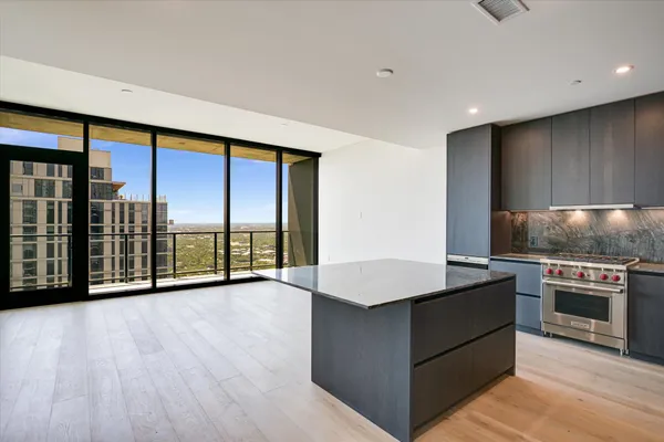 a view of kitchen with stainless steel appliances wooden floor and a large window