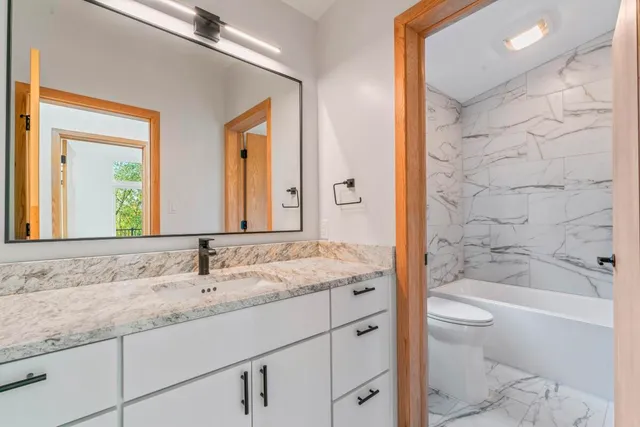 a bathroom with a granite countertop sink a toilet and shower