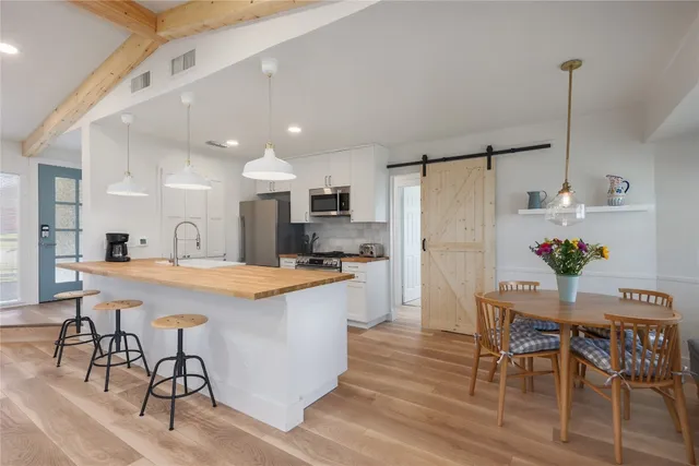a kitchen with stainless steel appliances a dining table chairs and white cabinets