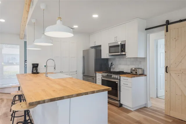 a kitchen with stainless steel appliances granite countertop a stove a refrigerator a oven a sink with a dining table and chairs