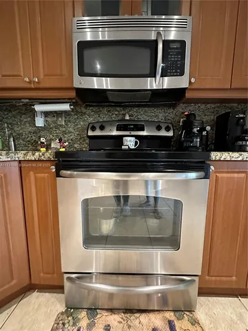 a kitchen with granite countertop a stove and a microwave