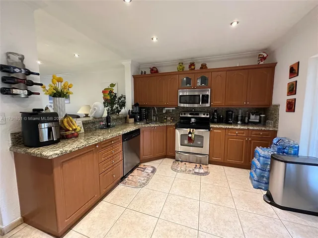 a kitchen with stainless steel appliances granite countertop a stove a sink and a refrigerator