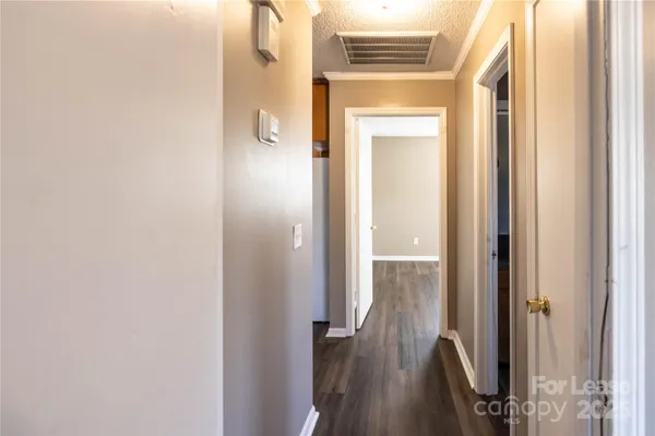 a view of a hallway with wooden floor and a bathroom