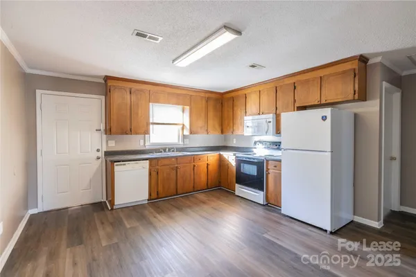 a kitchen with a refrigerator a stove top oven and wooden floors