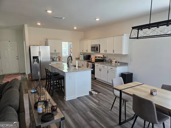a kitchen with kitchen island a stove a refrigerator and a dining table with wooden floor