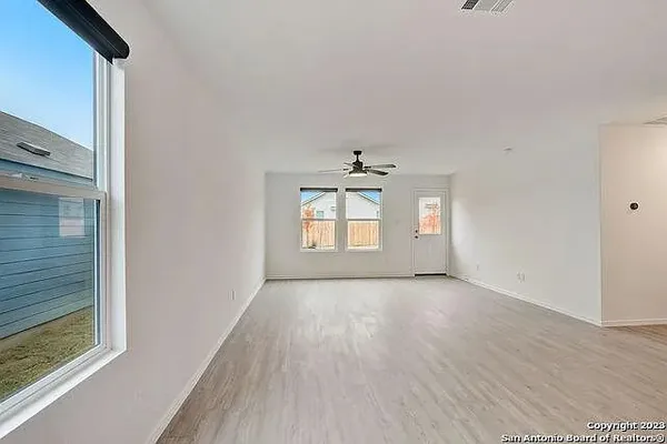a view of a big room with wooden floor and windows