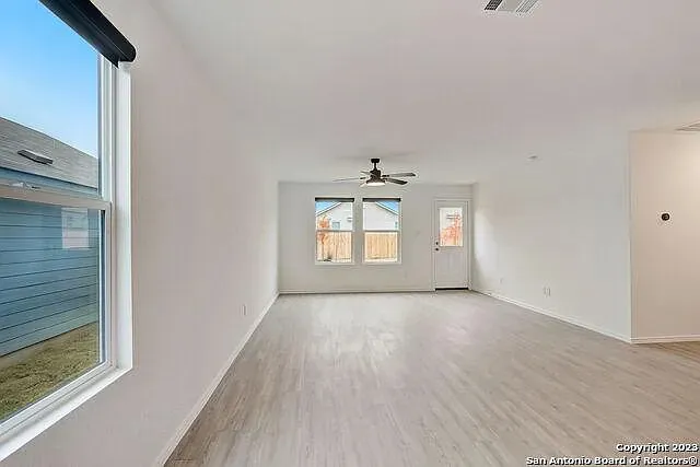 a view of a big room with wooden floor and windows