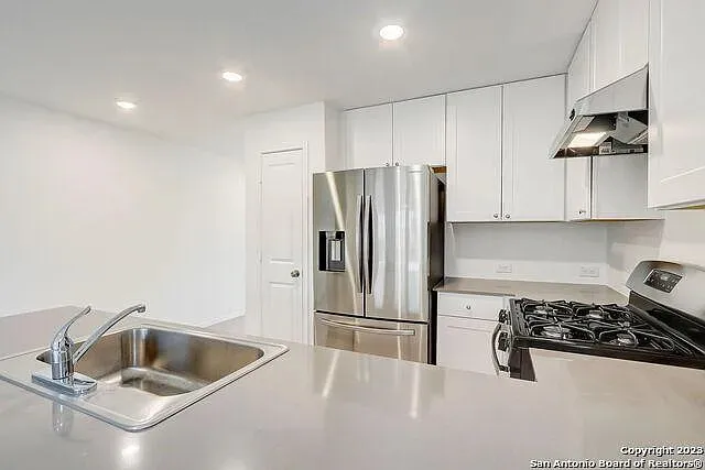 a kitchen with stainless steel appliances a sink a stove and refrigerator