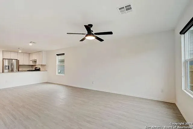 a view of a livingroom with a kitchen island a sink wooden floor and a ceiling fan