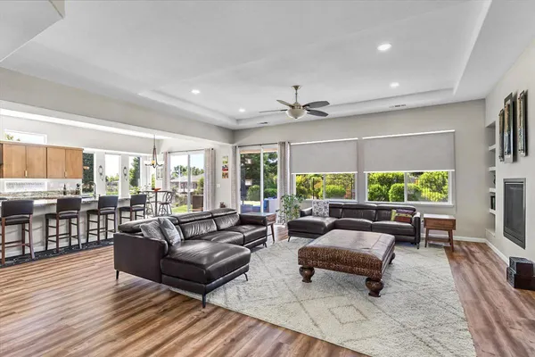 a kitchen with stainless steel appliances granite countertop a stove top oven a sink dishwasher a dining table and chairs with wooden floor