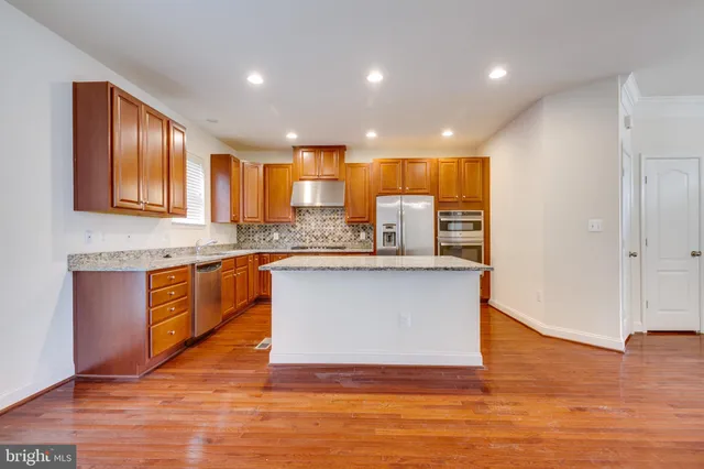 a kitchen with stainless steel appliances granite countertop a sink and a refrigerator