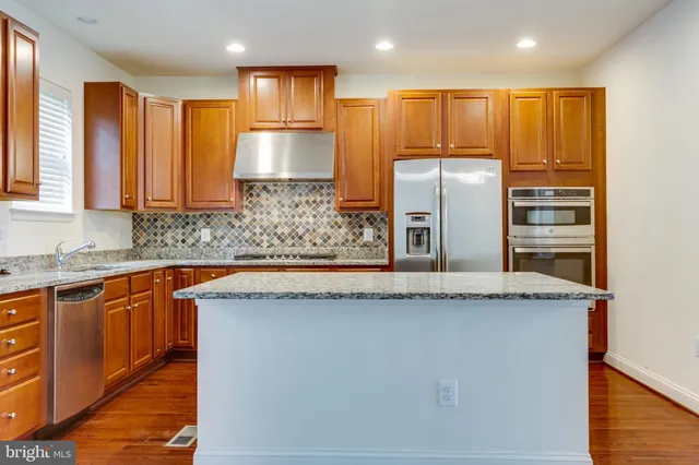 a kitchen with stainless steel appliances granite countertop a sink a stove a refrigerator and a microwave