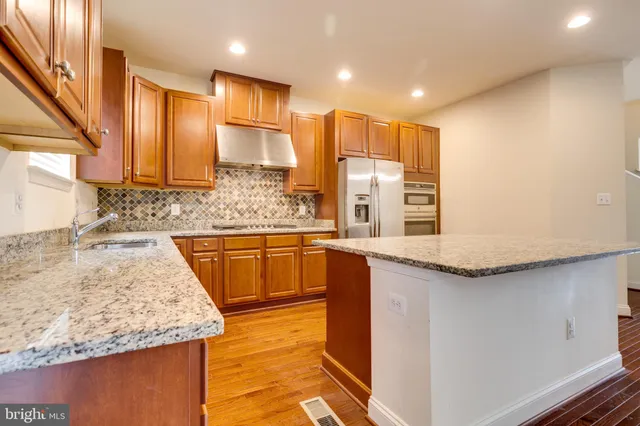 a kitchen with stainless steel appliances granite countertop wooden cabinets a sink and a large window