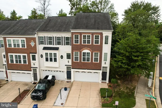 a view of a white house next to a yard with potted plants