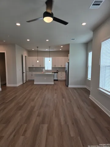 a view of kitchen with kitchen island wooden floors center island and stainless steel appliances