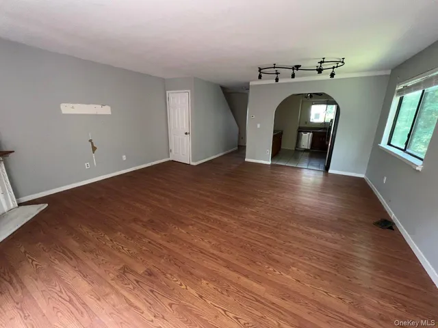 a view of empty room with window and wooden floor