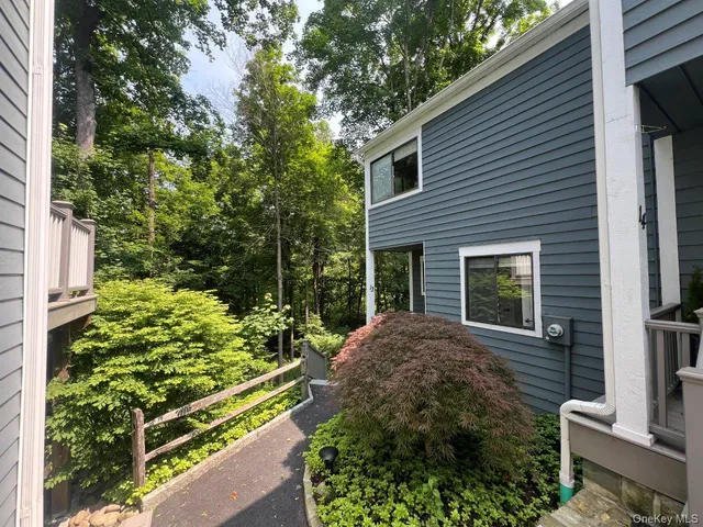 a view of a house with a small yard plants and large tree