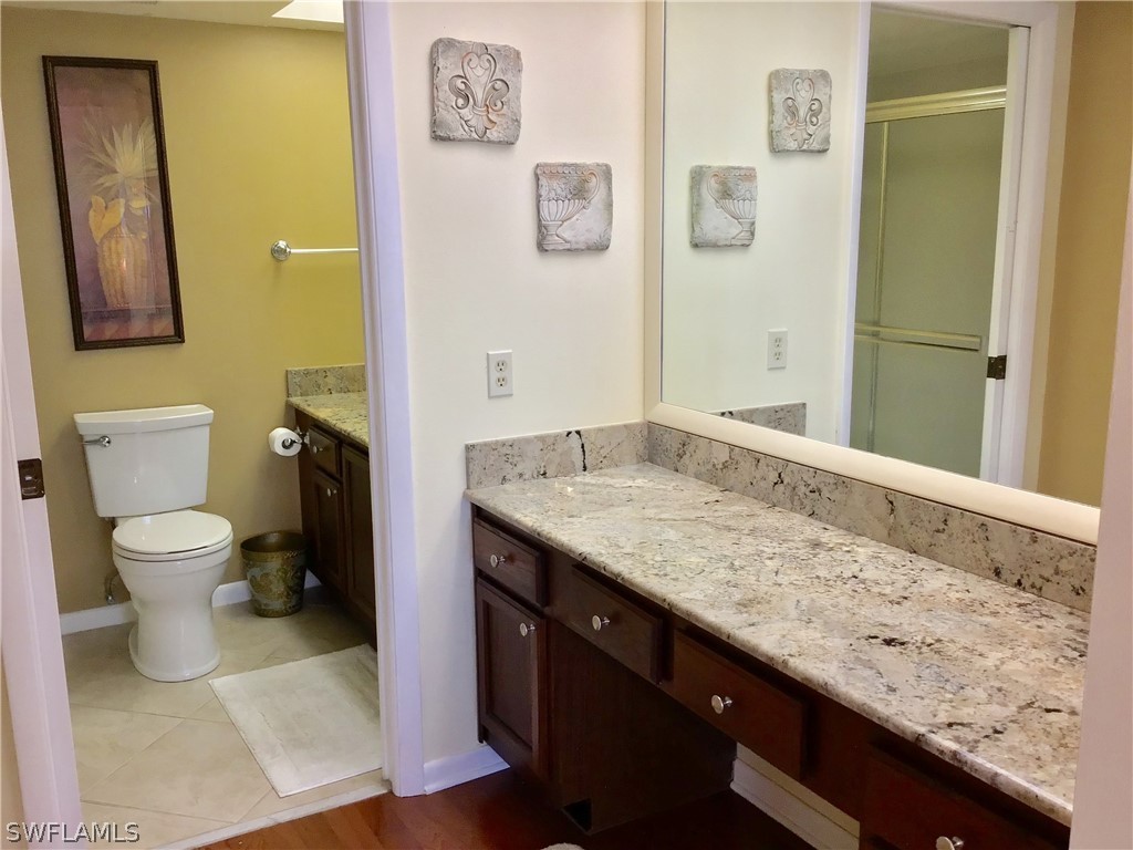 15021 Punta Rassa Road, Unit 704 Fort Myers, FL 33908 - Photo 8 of 18 a bathroom with a granite countertop sink a toilet and a mirror