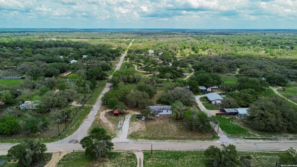 an aerial view of residential houses with outdoor space and trees
