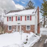 a front view of a house with a yard covered in snow