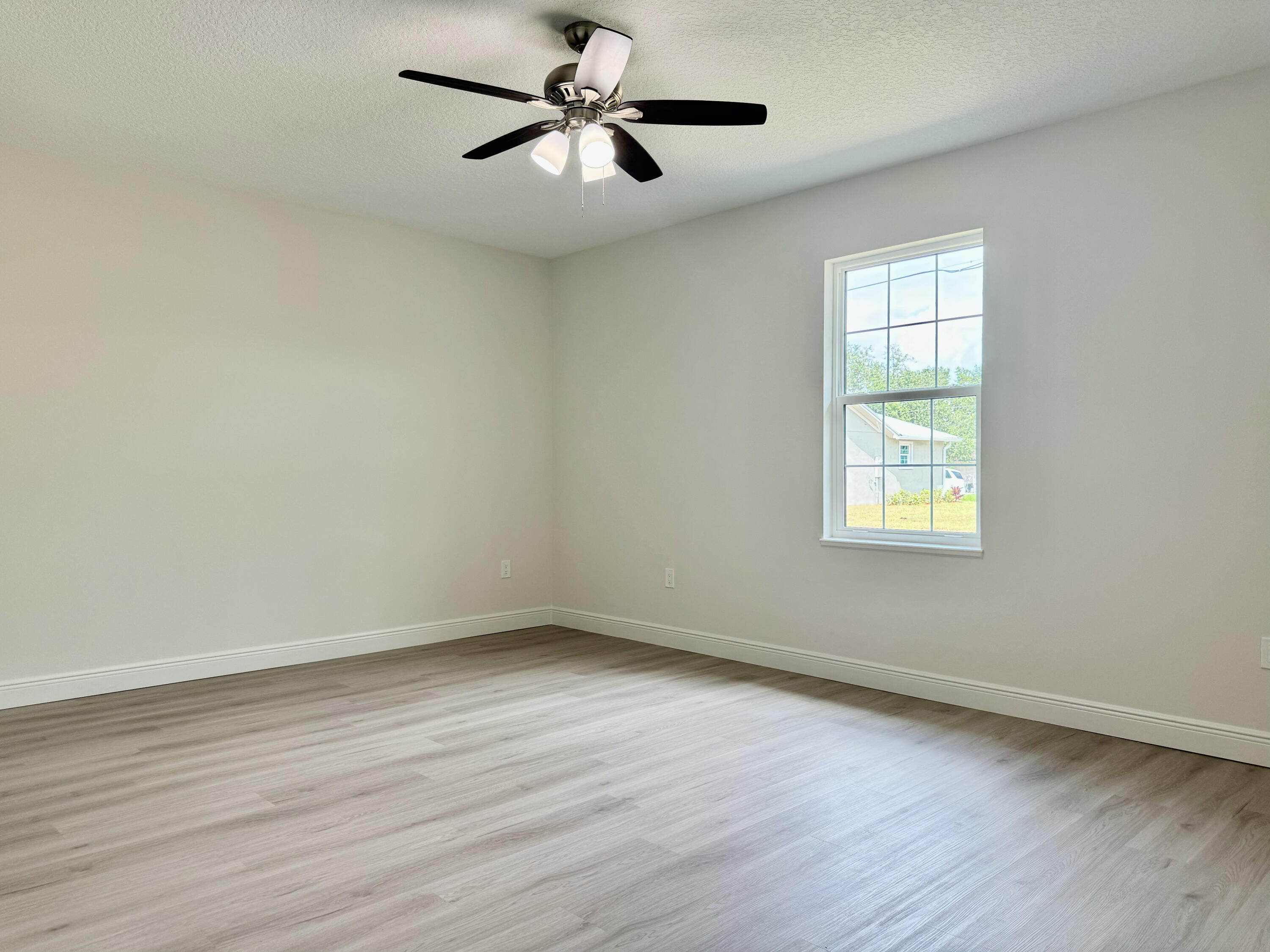 581 Southeast 36th Terrace Okeechobee, FL 34974 - Photo 6 of 19 a view of empty room with wooden floor and fan