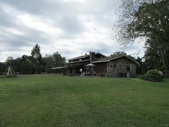 a view of a big house with a big yard and large trees