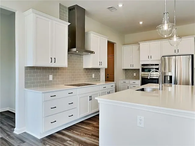 a kitchen with stainless steel appliances a refrigerator sink and white cabinets