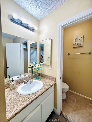 a bathroom with a granite countertop sink a toilet and a mirror