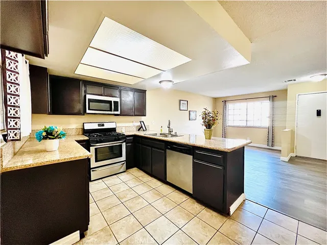 a kitchen with stainless steel appliances granite countertop a stove top oven a sink dishwasher and a microwave oven on the blue kitchen countertops