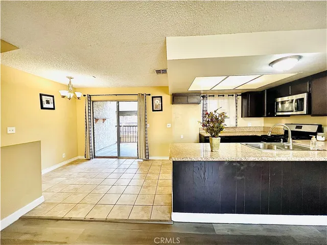 a living room with stainless steel appliances kitchen island granite countertop a sink and cabinets