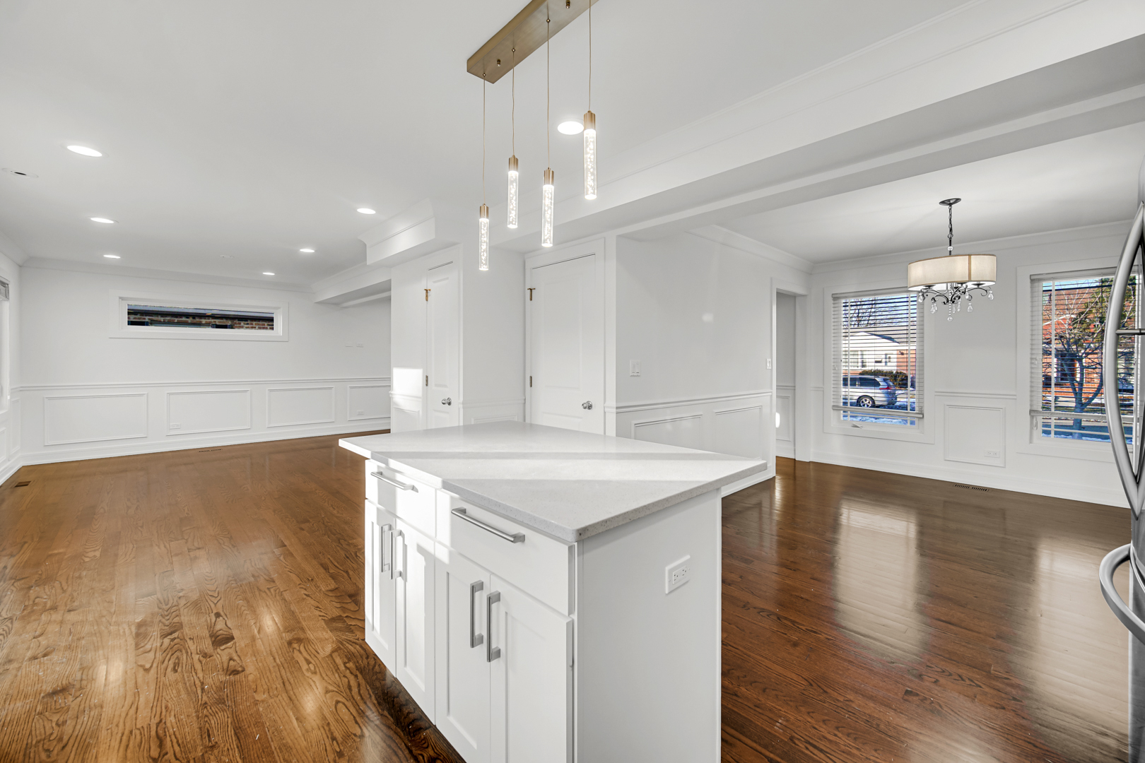 5817 Crain Street Morton Grove, IL 60053 - Photo 7 of 20 a view of a kitchen island a sink wooden floor and a living room