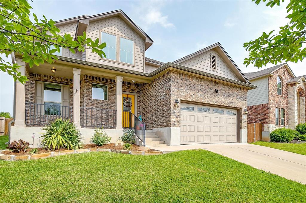 View of front of property with covered porch, brick siding, a front lawn, concrete driveway, and an attached garage