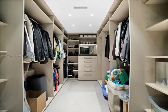 a view of walk in closet with clothes and shoes