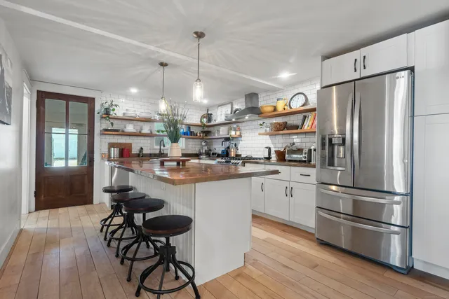 a kitchen with stainless steel appliances granite countertop a sink a stove and a wooden floors