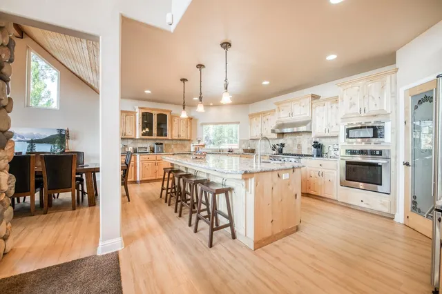 a kitchen with stainless steel appliances granite countertop a refrigerator a stove top oven a sink dishwasher and white cabinets with wooden floor