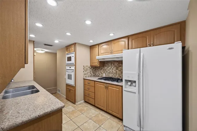 a kitchen with stainless steel appliances granite countertop a refrigerator and a stove