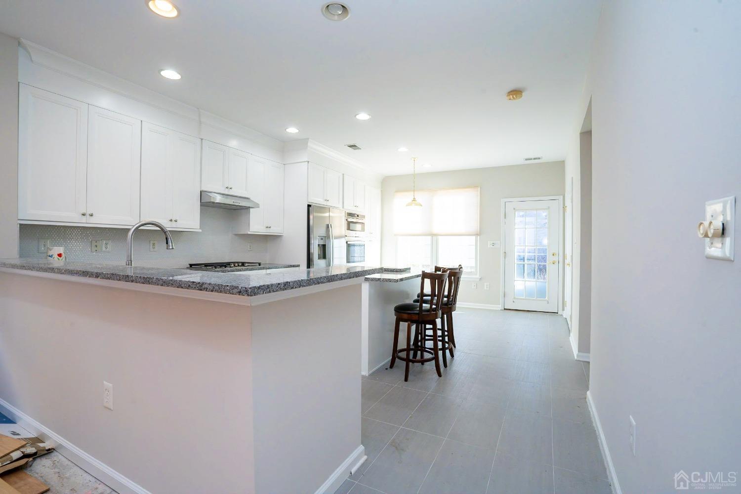 7 Stony Path Dayton, NJ 08810 - Photo 10 of 33 a kitchen with kitchen island granite countertop wooden floors and white cabinets