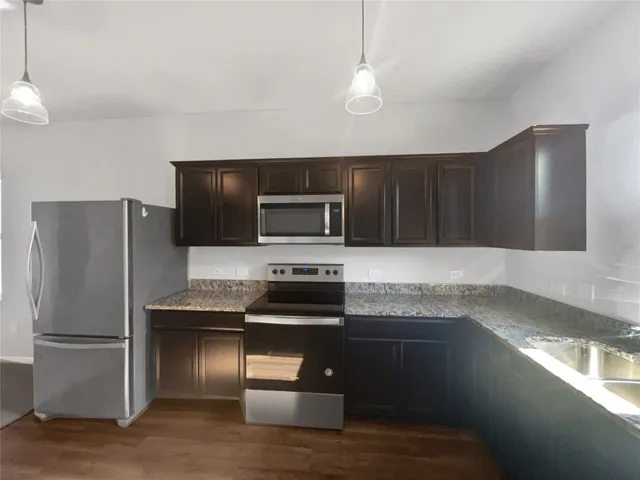 a kitchen with granite countertop a refrigerator and a stove top oven