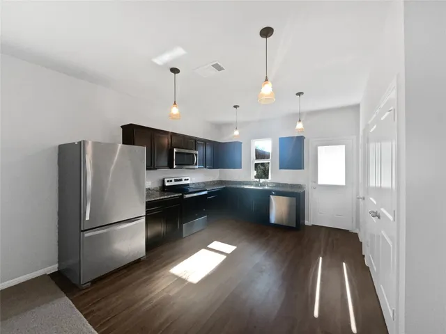 a kitchen with stainless steel appliances granite countertop a refrigerator a sink dishwasher a stove and a refrigerator