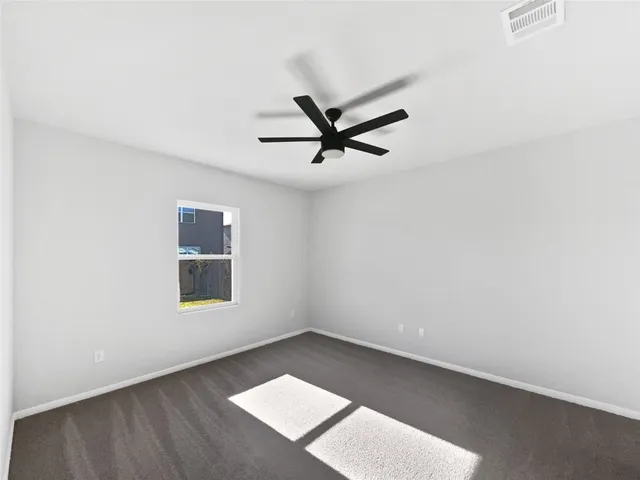 an empty room with a window and a ceiling fan