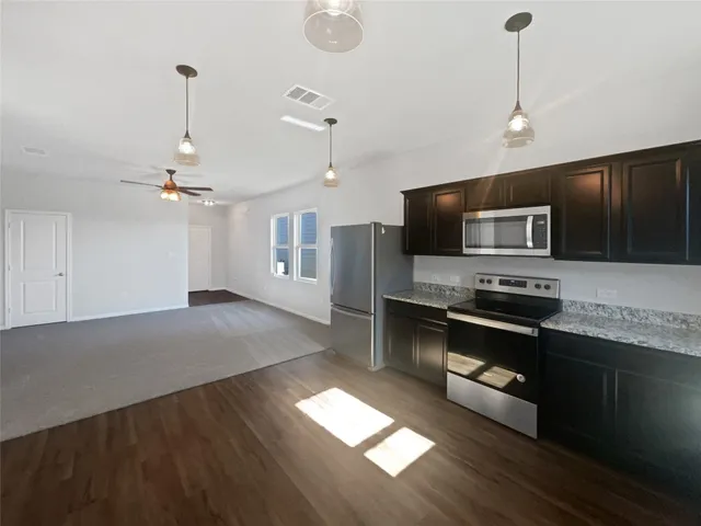 a kitchen with stainless steel appliances granite countertop a stove a refrigerator and a microwave