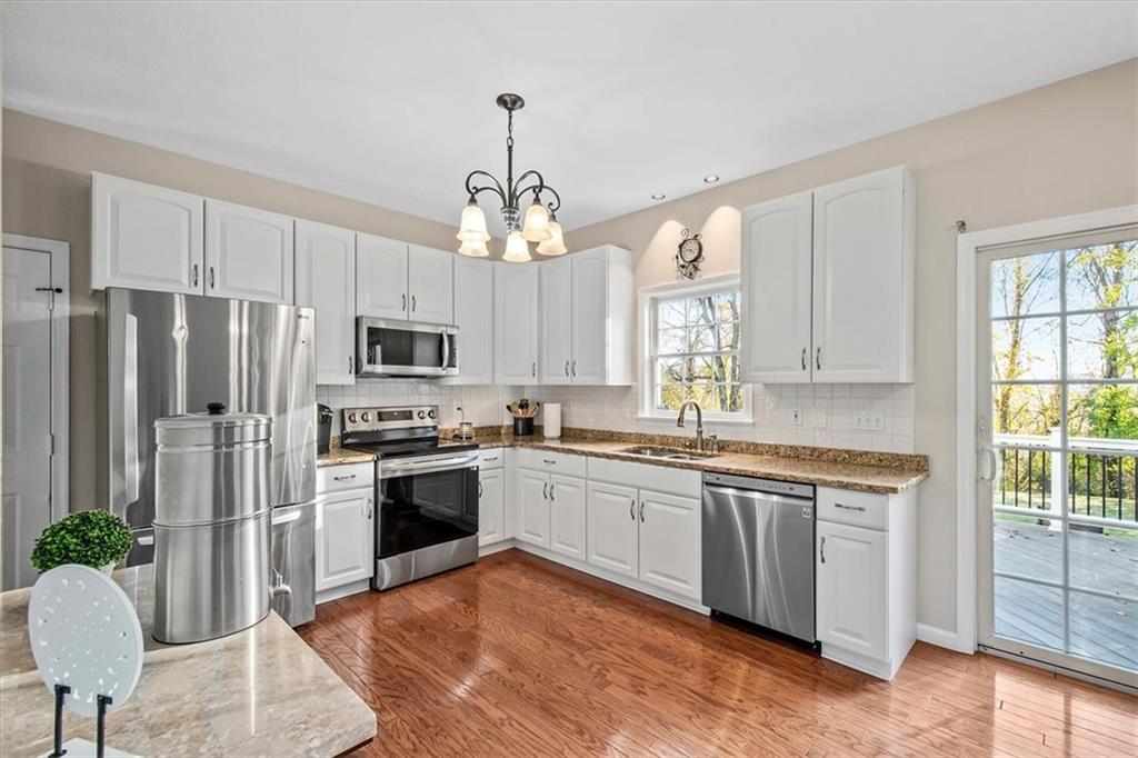 386 Pine Ridge Drive Venetia, PA 15367 - Photo 6 of 25 a kitchen with stainless steel appliances granite countertop a refrigerator a sink dishwasher a stove and white cabinets with wooden floor